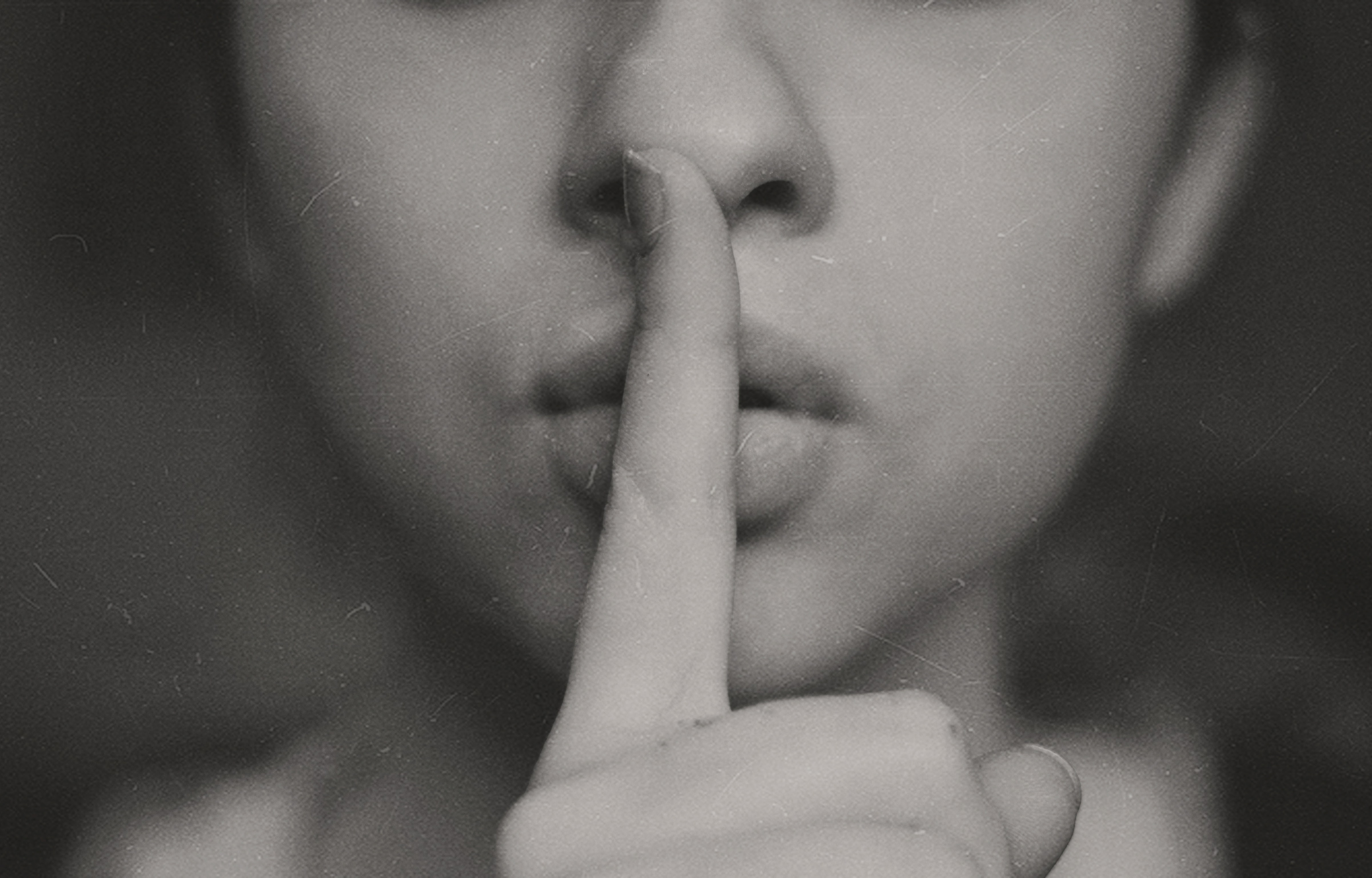 A women holding up her finger in front pursed lips.