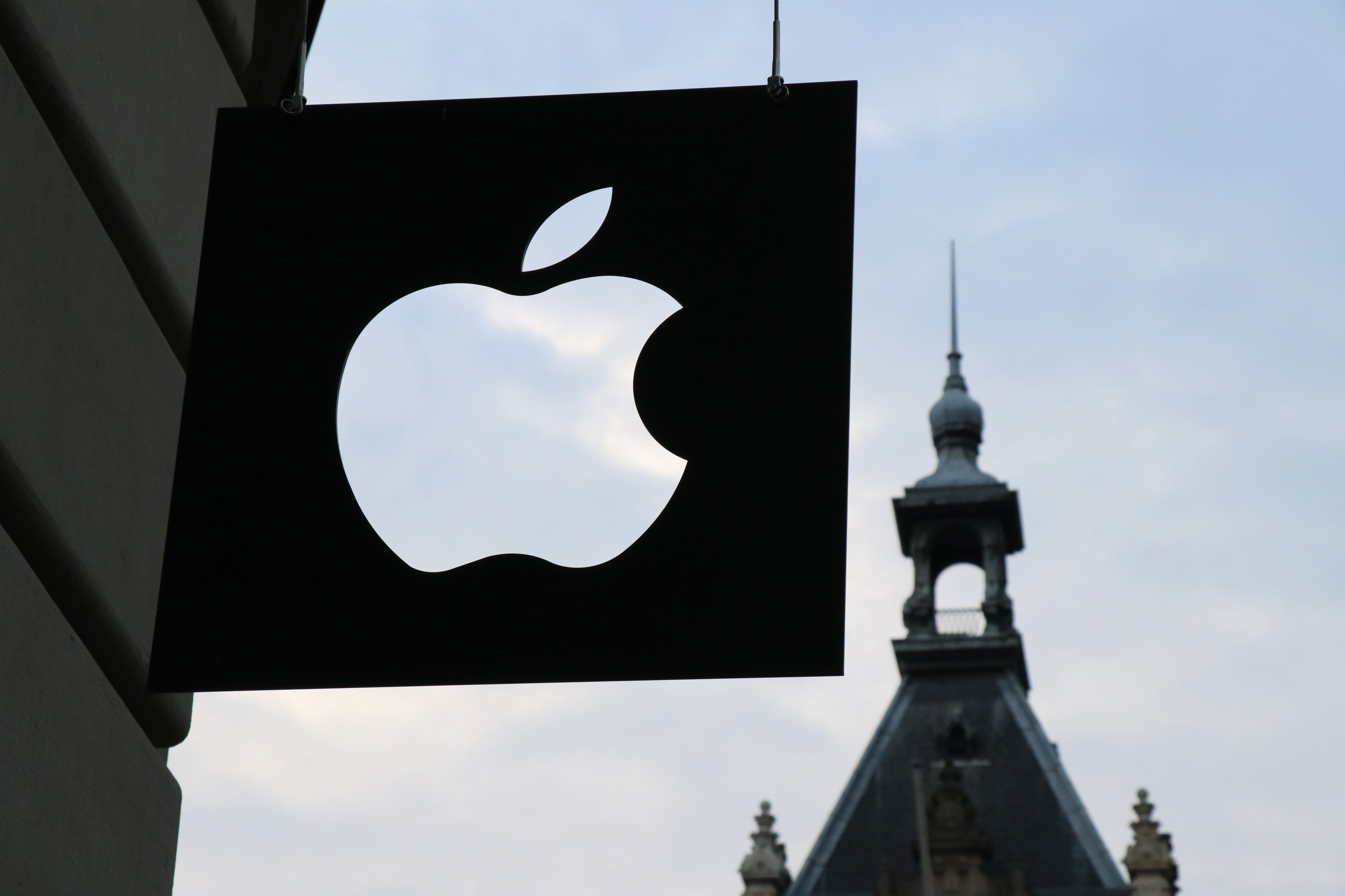 Apple logo with a building spire in the background.