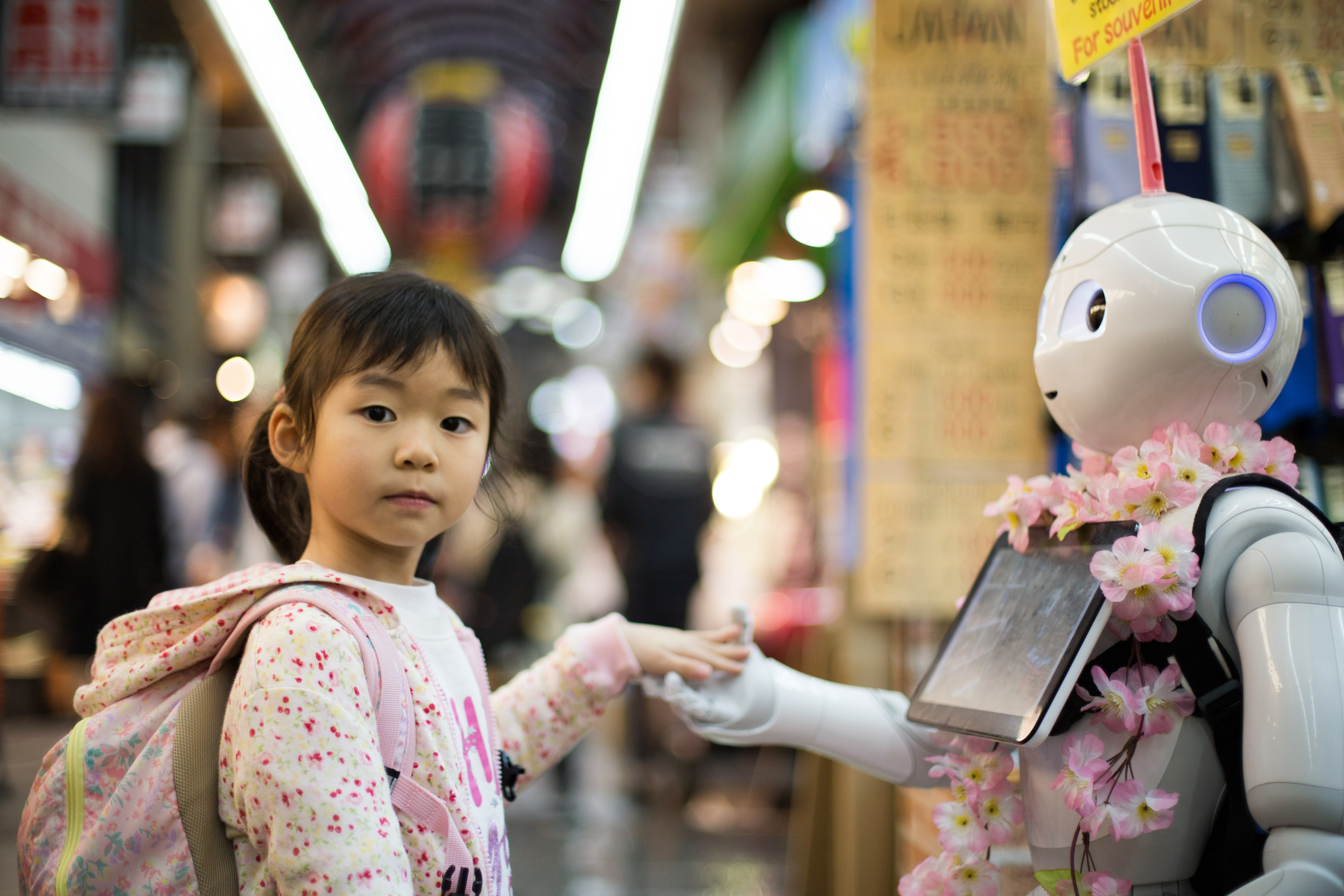 Cute Asian girl holding a robot's hand
