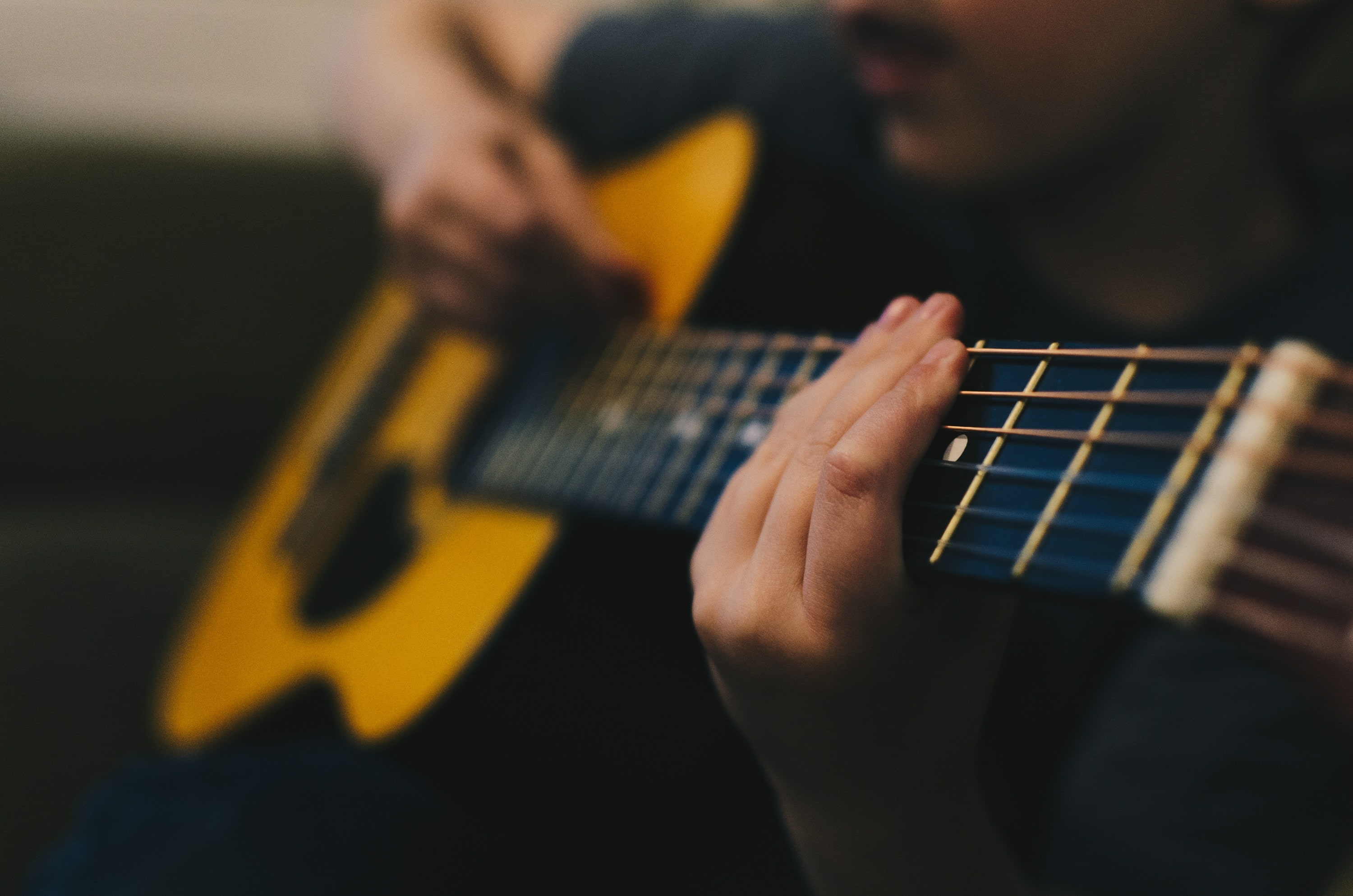 Man playing a yellow acoustic guitar.