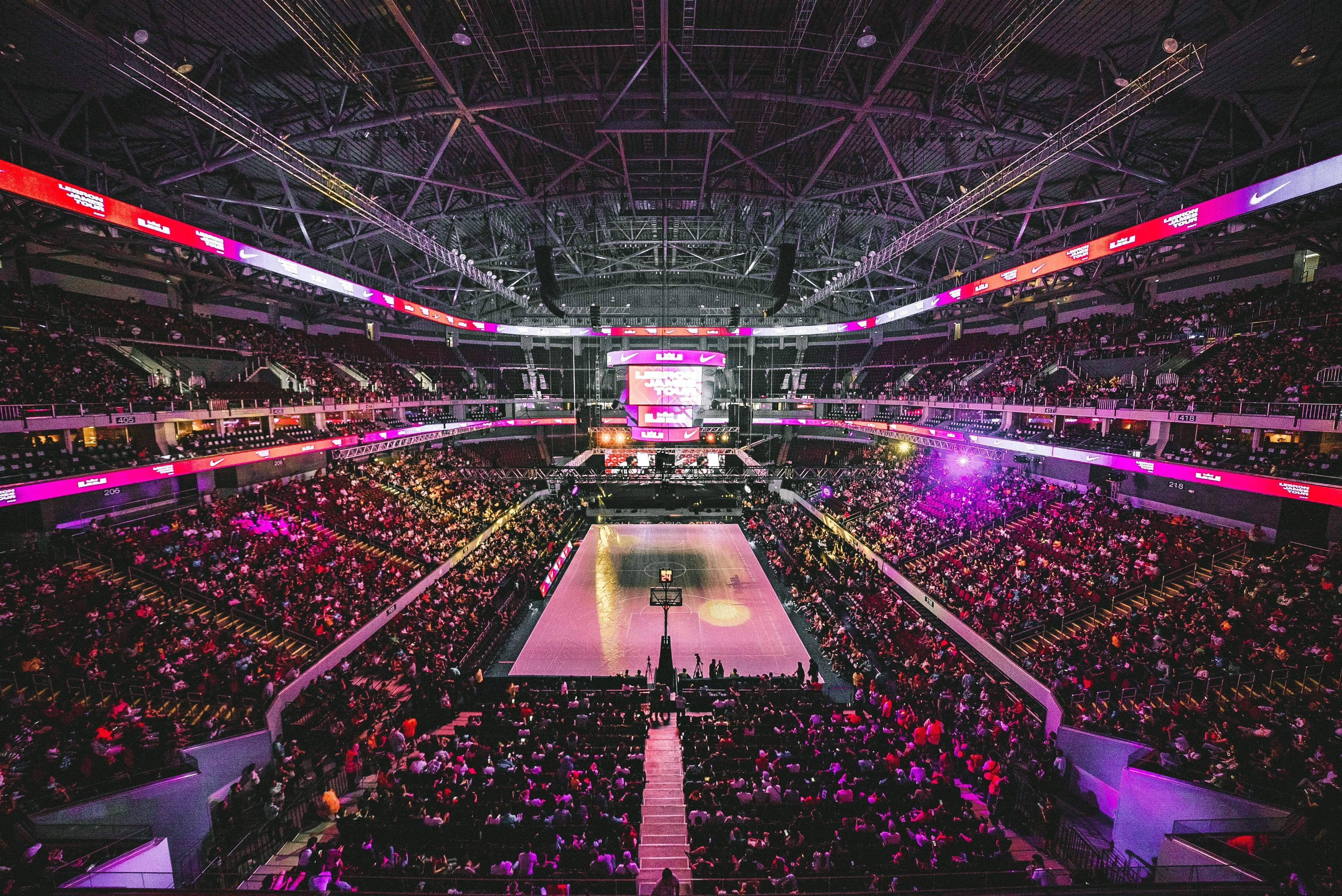 Crowded basketball stadium with neon lights.