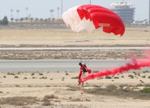 a man flying a parachute lands safely on the ground