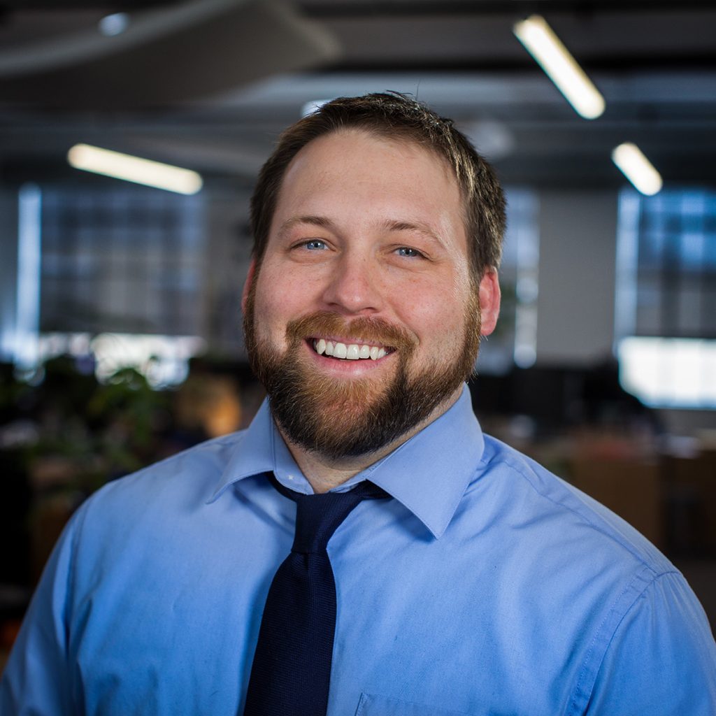 Web designer in blue shirt and tie smiling at the camera.