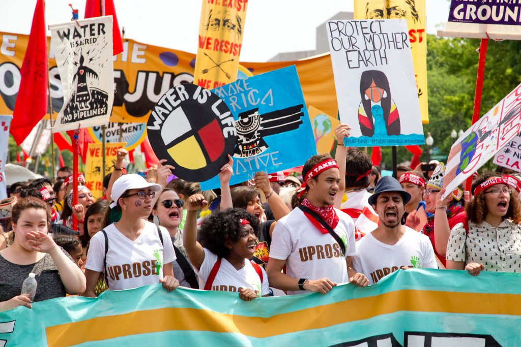 Activists at a clean water march with colorful signs and flags.