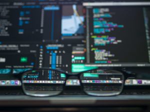 A pair of prescription glasses in front of a computer monitor.