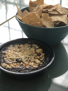 Tortilla chips and mole in bowls on a table.