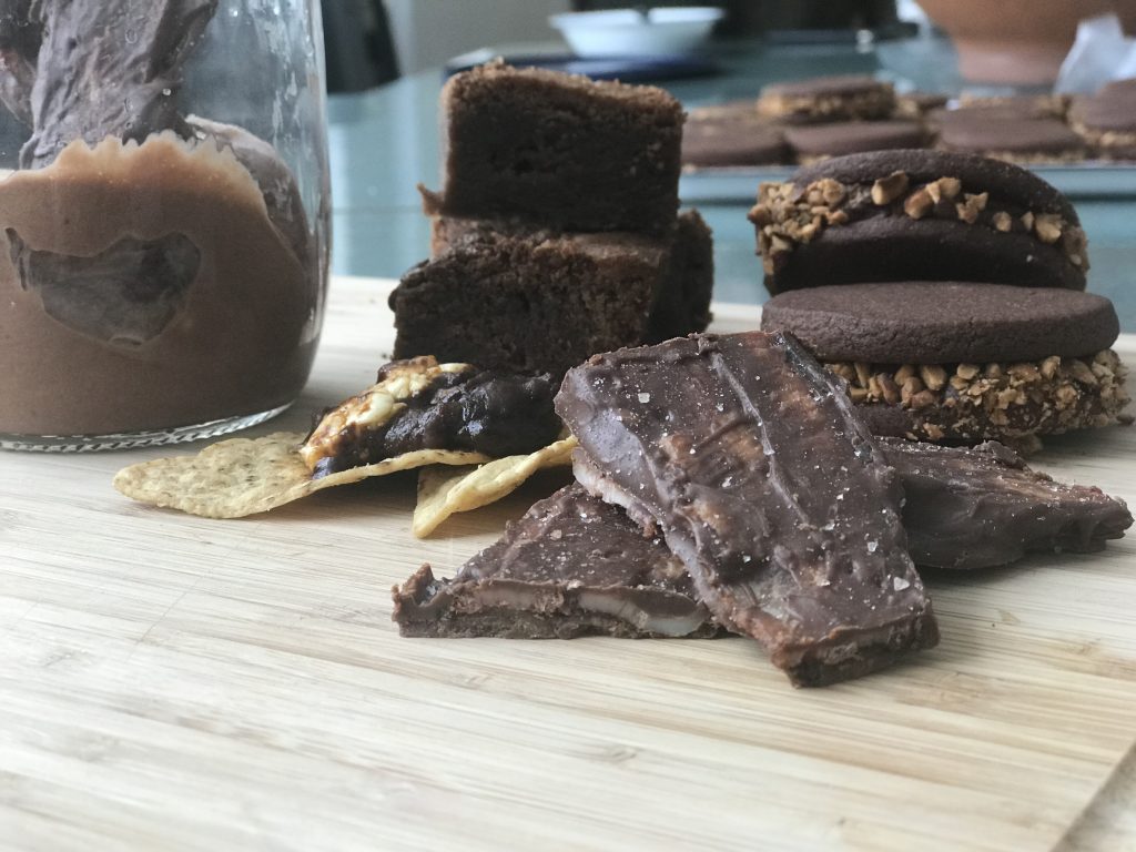 Various chocolate snacks and cookies on a wooden cutting board.