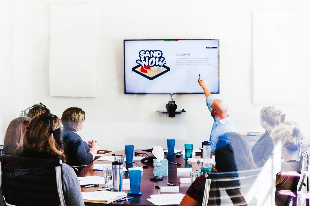 Marketing employees around a table for a SandWoW strategy meeting.