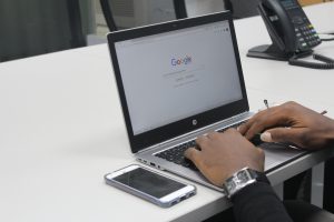 Person sitting at a table performing a Google search on their laptop.