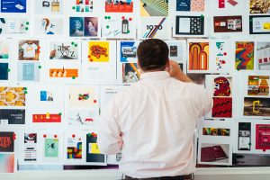 A male employee creating a collage of graphic design styles for a website redesign activity.