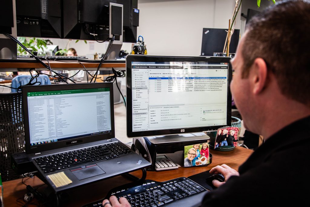 A male marketing employee working on his laptop with extra monitor.