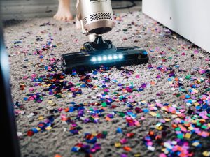 A modern vacuum cleaner vacuuming up glitter on carpet.