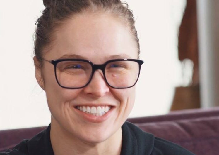 ronda rousey, a professional wwe wrestler smiles while wearing black framed glasses