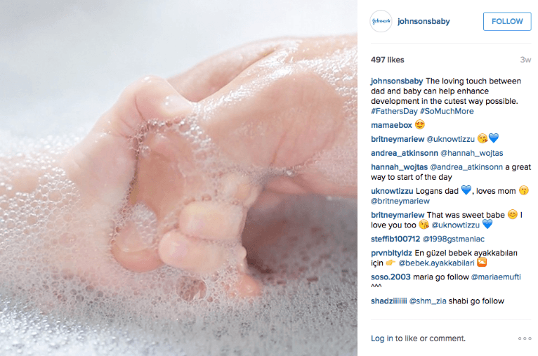 screenshot of instagram post by johnsonsbaby showing a baby hand holding an adult hand in a soapy tub of water