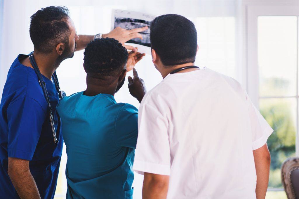 three medical professionals standing together gesturing mid-conversation
