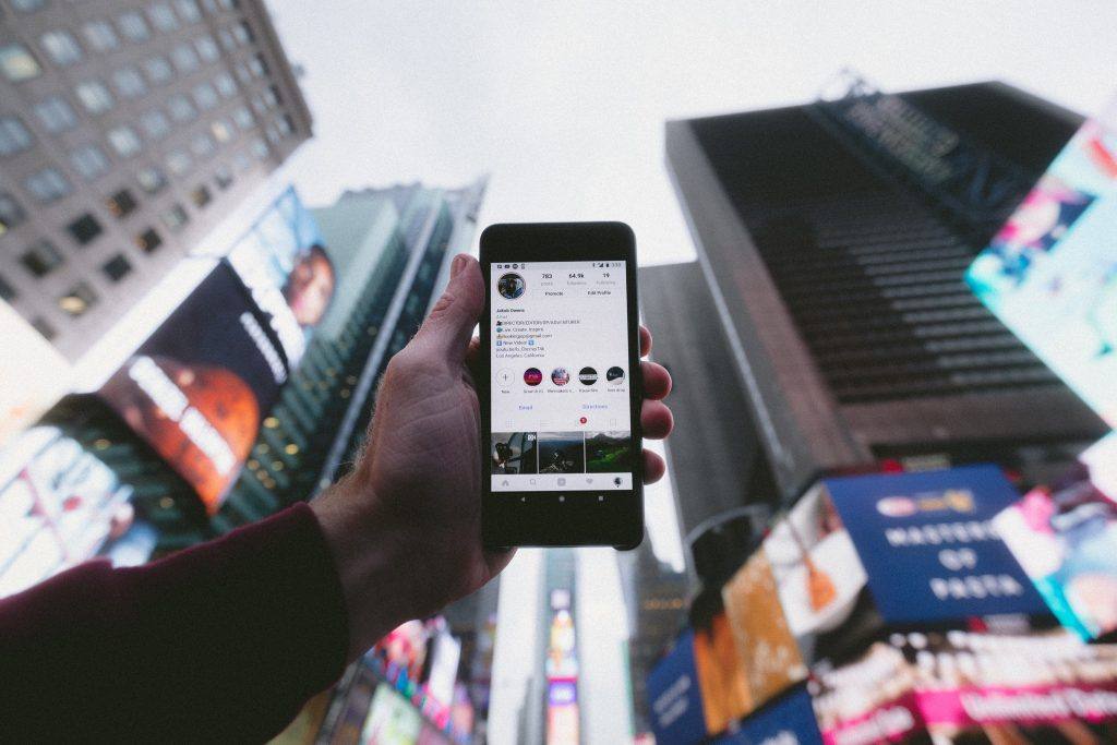 iphone screen held to the sky with the tops of skyscrapers