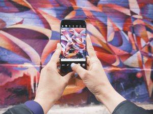 phone open to instagram photo capture screen in front of a colorful wall mural