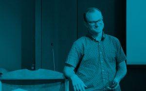 man smiling with elbow resting on podium