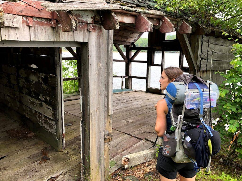 woman wearing hiking backpack walks through ruined building