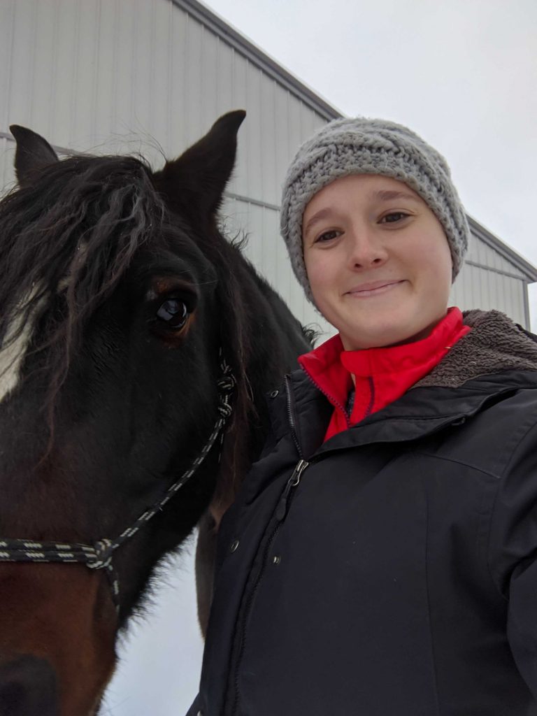 woman takes picture of herself while walking with a horse