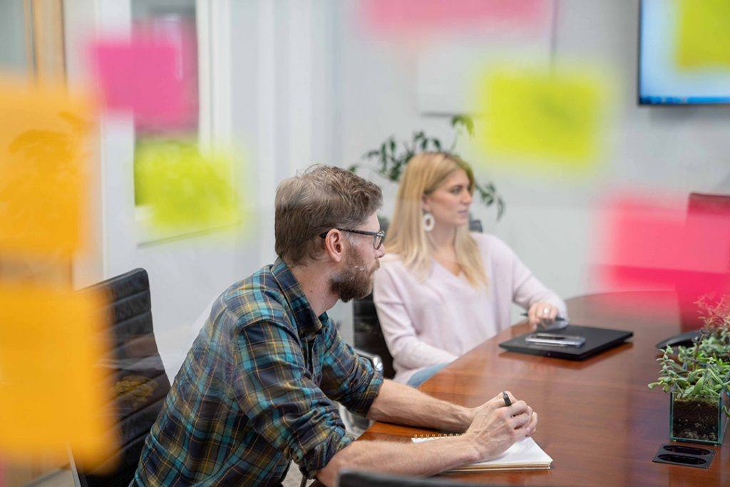 Two marketing experts discuss process, with sticky notes in the foreground