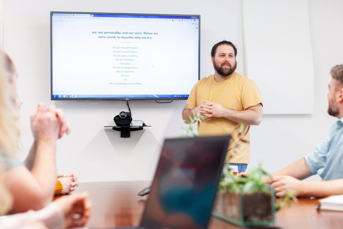 Man making a marketing and branding presentation to a conference room of people.