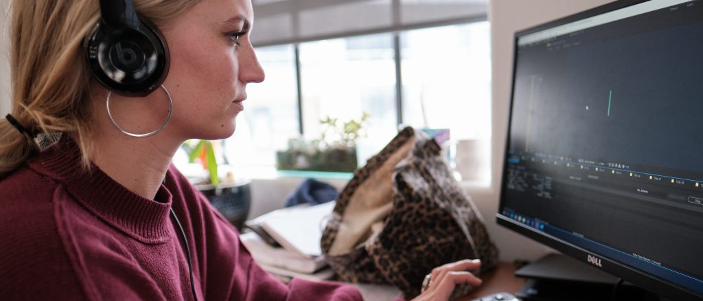 Woman using video editing software while wearing headphones