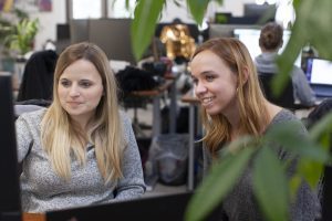 two women looking at a computer screen, smiling