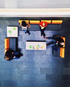 a top down view of four college students studying and on laptops while sitting on couches