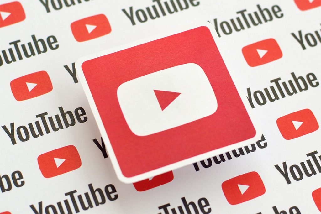 Youtube logo sticker on pattern printed on paper with small youtube logos and inscriptions. YouTube is Google subsidiary and American most popular video-sharing platform