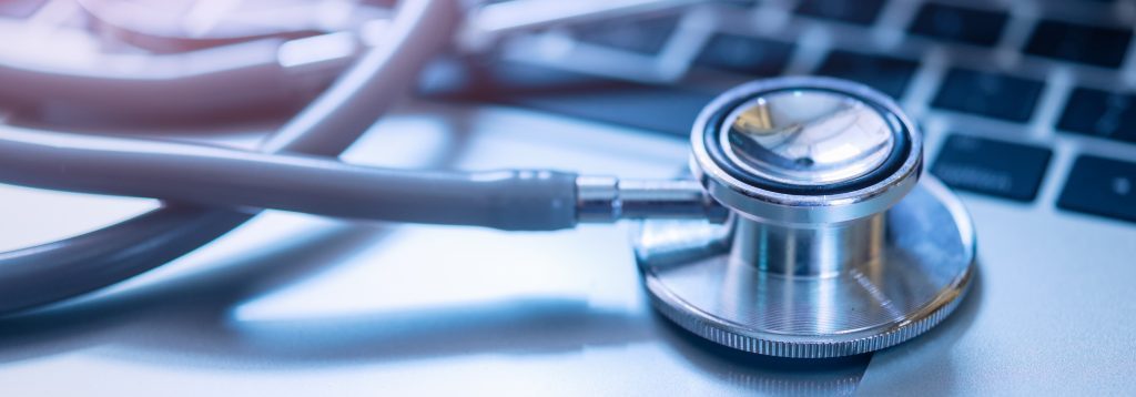 Stethoscope on a table with a laptop next to it