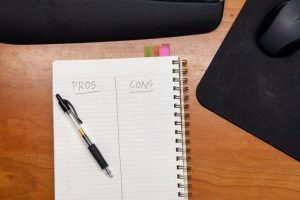 Notebook on a desk with a pros and cons list