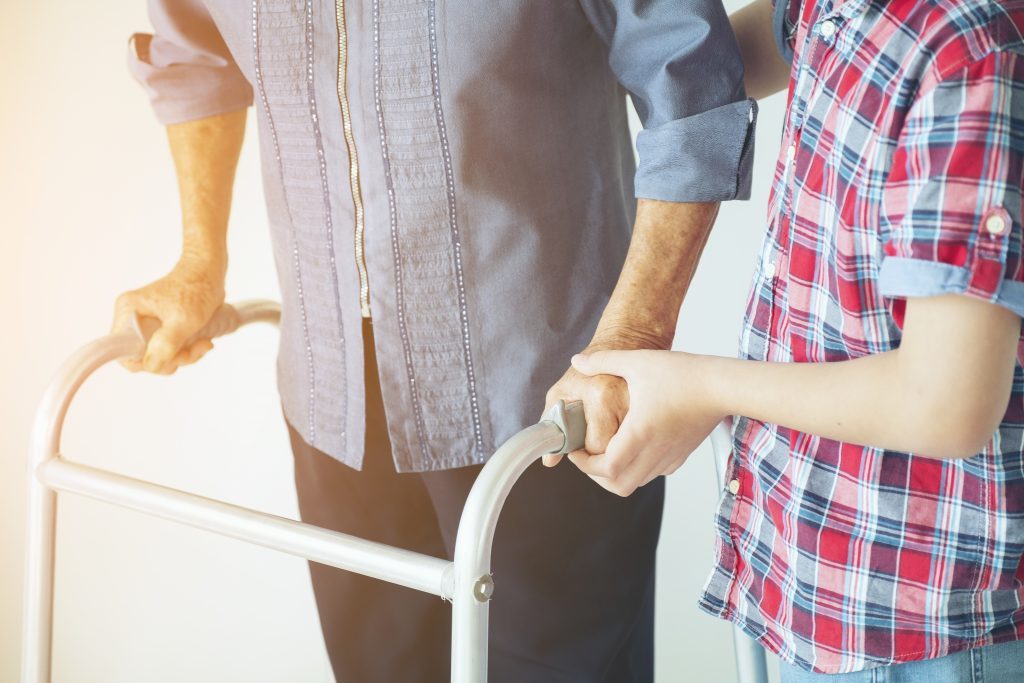 Grandmother Senior woman and grandson are holding onto a walker during physical rehab