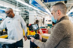 an experienced video marketing expert wearing a mask uses his camera to create a video in a shop