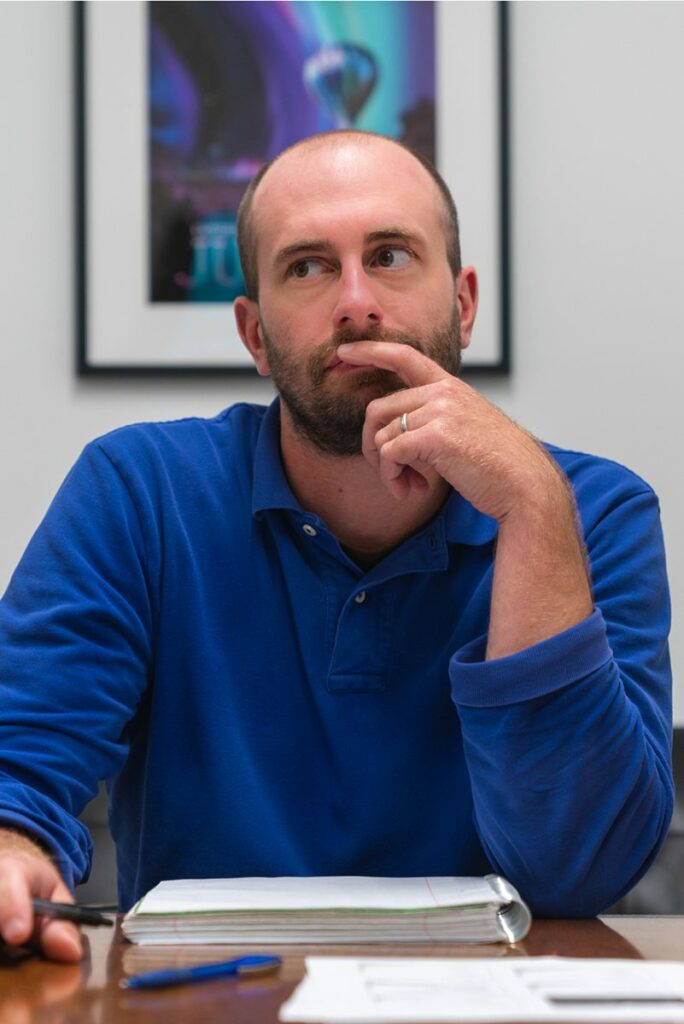 a man sits at a meeting table with his notes while thinking