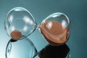 An hourglass laying on its side on a glassy table illustrates how the time it takes seo to work varies