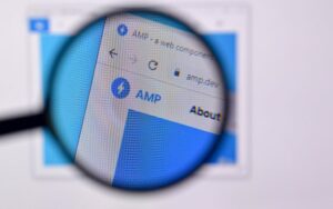 a magnifying glass hovers over a computer screen showing "amp" for accelerated mobile pages