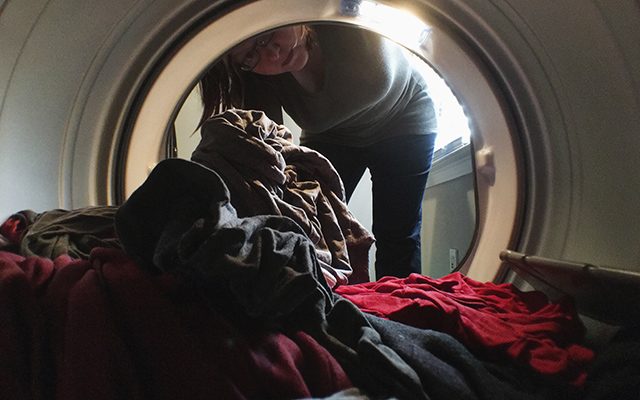 a look from inside a dryer pointing out at a woman taking clothes out