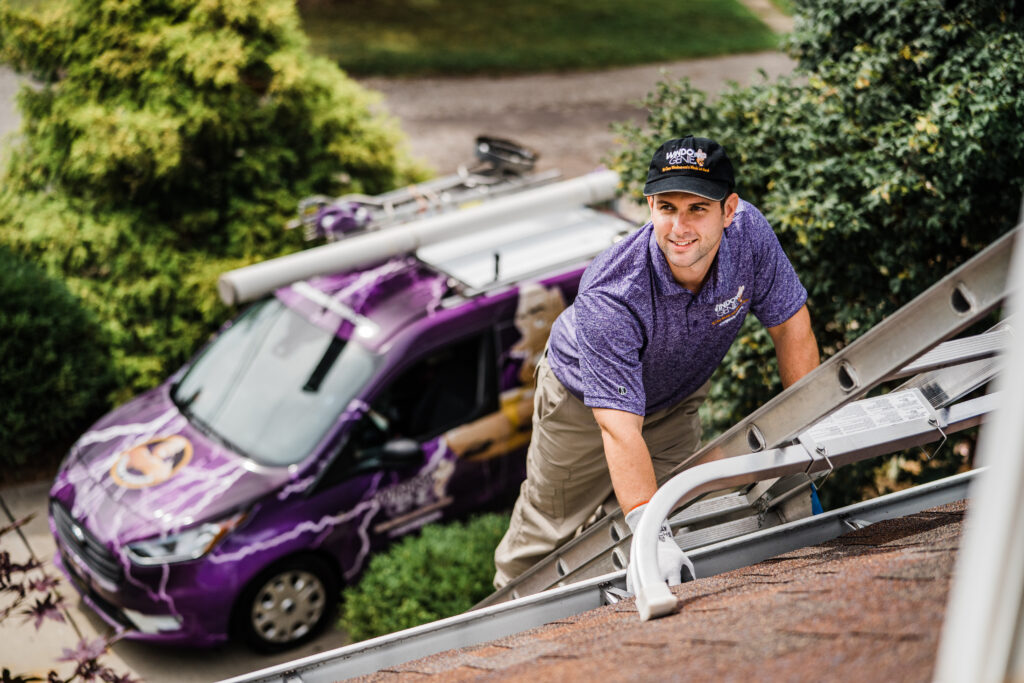 a window worker looks up while climbing a ladder to a roof