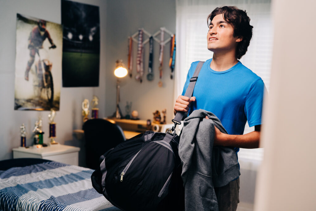 a young teenager looks around his room before heading off to college