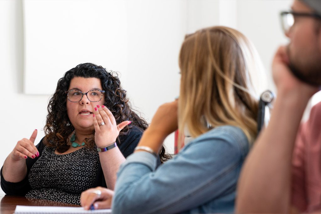 Several Oneupweb employees discussing strategy while sitting around a conference table.