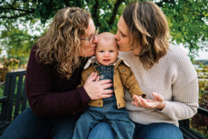 Laura Payne sits with her wife kissing their child