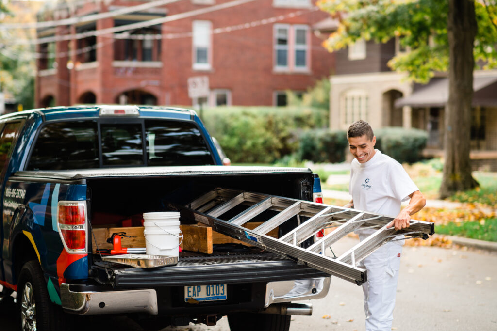 a five star painting employee removes a ladder from the back of a pickup truck to work