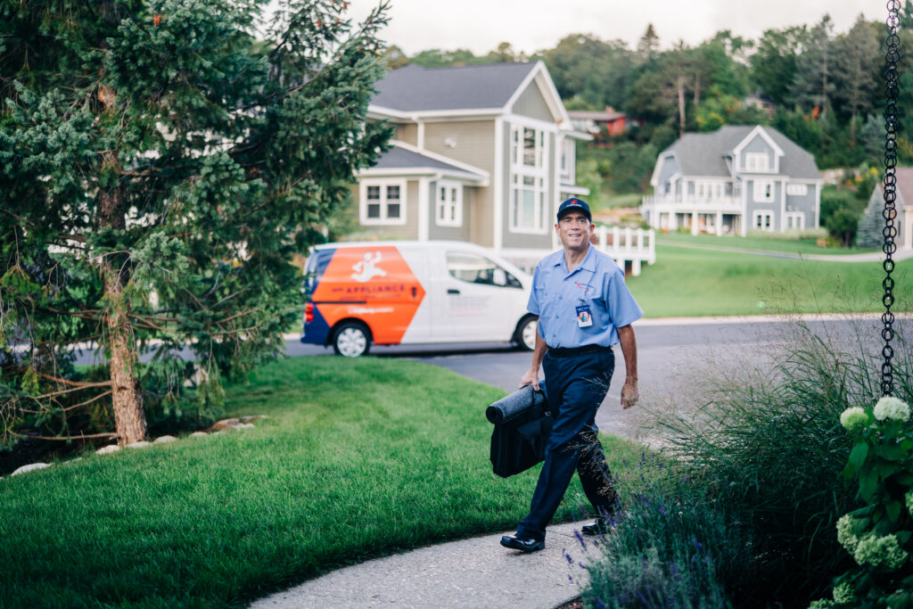 mr appliance employee walking from vehicle to house with tools