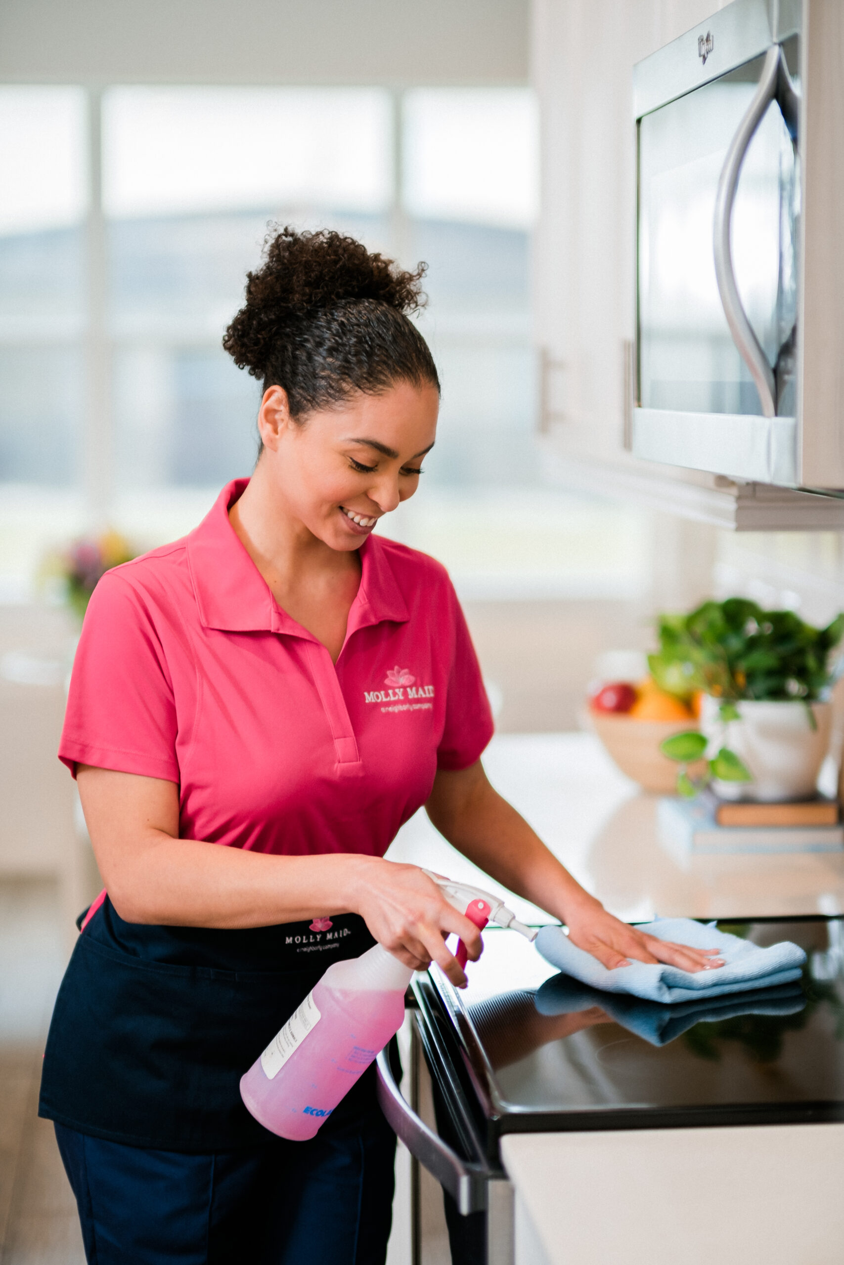 a molly maid employee cleans the stove of a nicely decorated home