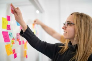 A Oneupweb strategist places a note on a whiteboard.