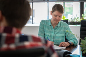 A female market jots down a note during a meeting.