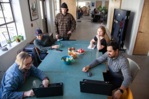 A team of marketers evaluate data at a large green table.