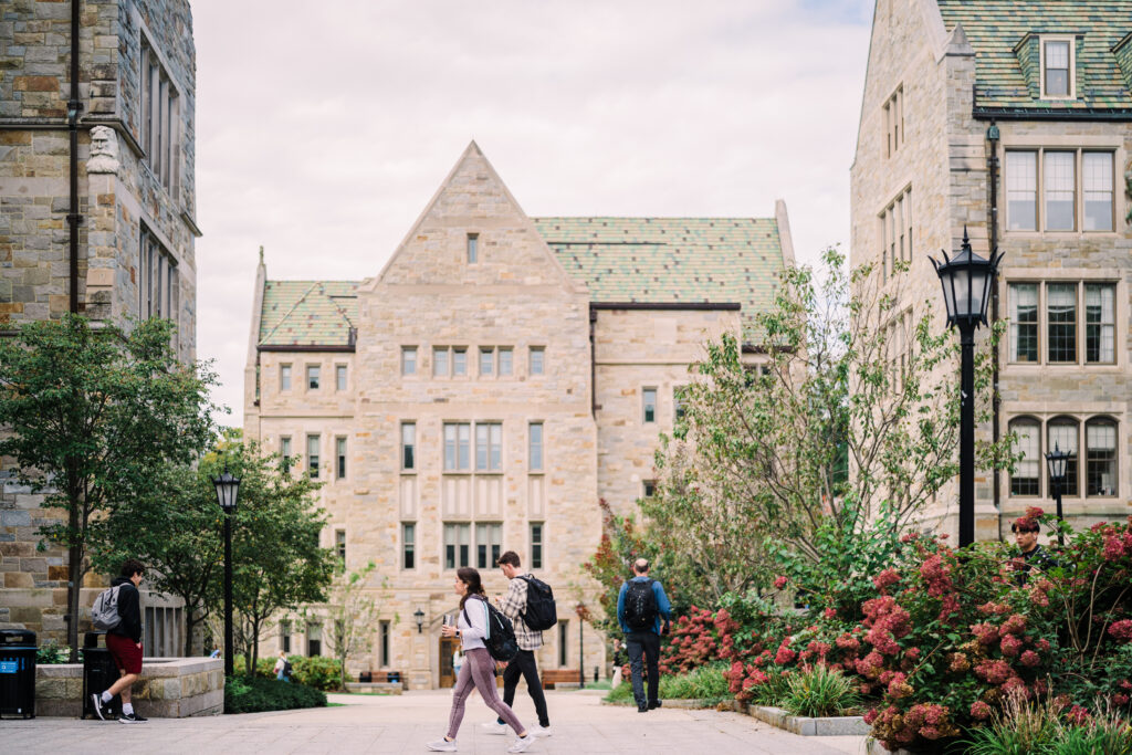 students on a college campus walk through the old buildings