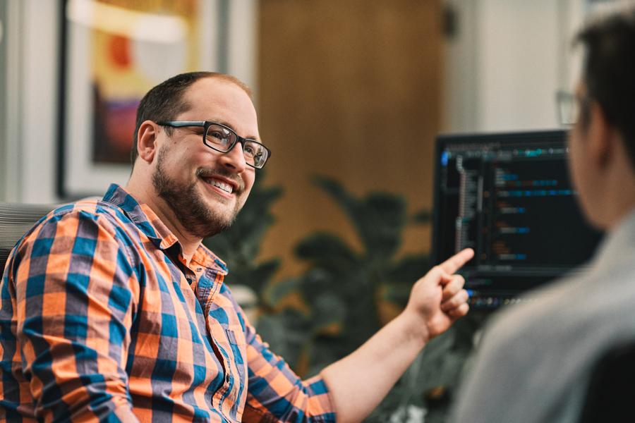 a oneupweb developer points to code on a computer screen